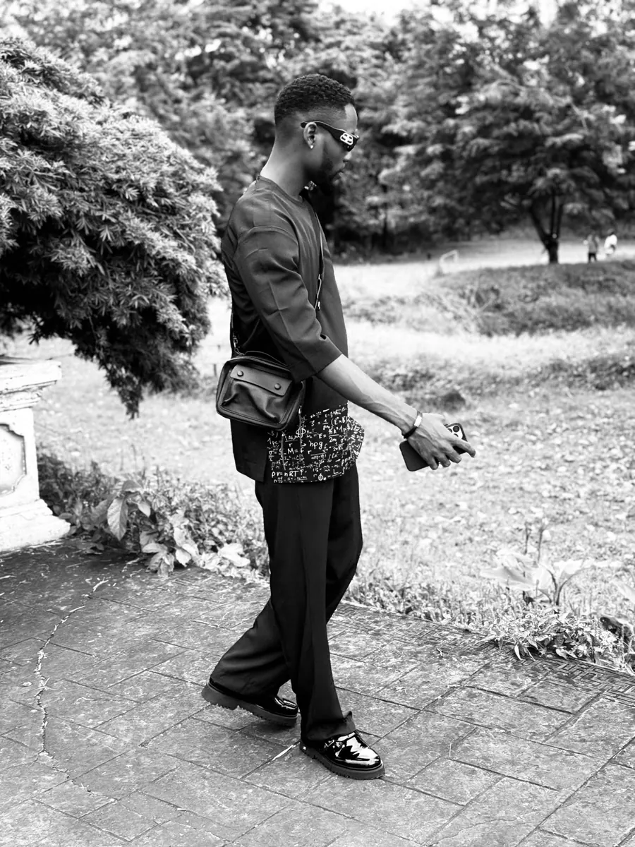Foto ojii na ọcha nke Ifechi Nwaorisa na-eje ije n'ụzọ, yi ugogbe anya, obere akpa akpụkpọ anụ n'obi ya